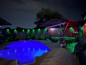 Ein Garten mit Schwimmbad, Holzterrasse und Gartenmöbeln.