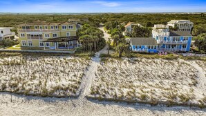 Ein Küstenwohngebiet mit Häusern direkt am Strand, darunter ein zweistöckiges Haus mit Balkon und ein blaues Haus mit Veranda.