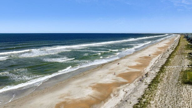 Ein Strand mit Wellen, einem sandigen Ufer und blauem Himmel.