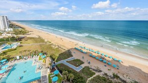 Ein Strandresort mit Swimmingpool, Strandstühlen und Blick auf den Ozean.