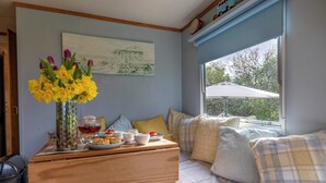 Ein Zimmer mit Bett, Tisch mit Frühstücksangeboten, Blumen in einer Vase und einem Fenster mit Blick.