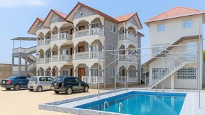 Un edificio de varios pisos con balcones, piscina y escalera.