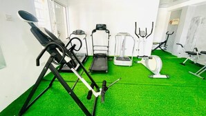 Un gimnasio con diversos equipos de ejercicio, incluyendo una cinta de correr, elíptica y bicicleta estática.