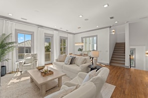 A spacious living room with a large window, a staircase, and a dining area. - ⭐Pelican Watch-Luxury Coastal Retreat w/ 5 Balconies Nea Rosemary & Alys⭐ (Seacrest Beach)