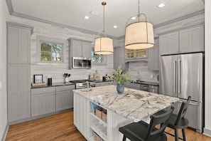 A modern kitchen with grey cabinetry, a central island with a marble countertop, stainless steel appliances, and pendant lighting. - ⭐Pelican Watch-Luxury Coastal Retreat w/ 5 Balconies Nea Rosemary & Alys⭐ (Seacrest Beach)