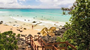 A beach with clear turquoise water, people swimming, and a wooden staircase leading down to the shore. - Luxury Home in Countryside Setting close to Beaches, Bushland, Restaurants/Shops (North Arm)