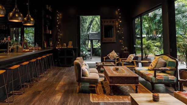 A bar area with high stools, a seating area with sofas and a coffee table, and large windows with a view of greenery. - Luxury Home in Countryside Setting close to Beaches, Bushland, Restaurants/Shops (North Arm)