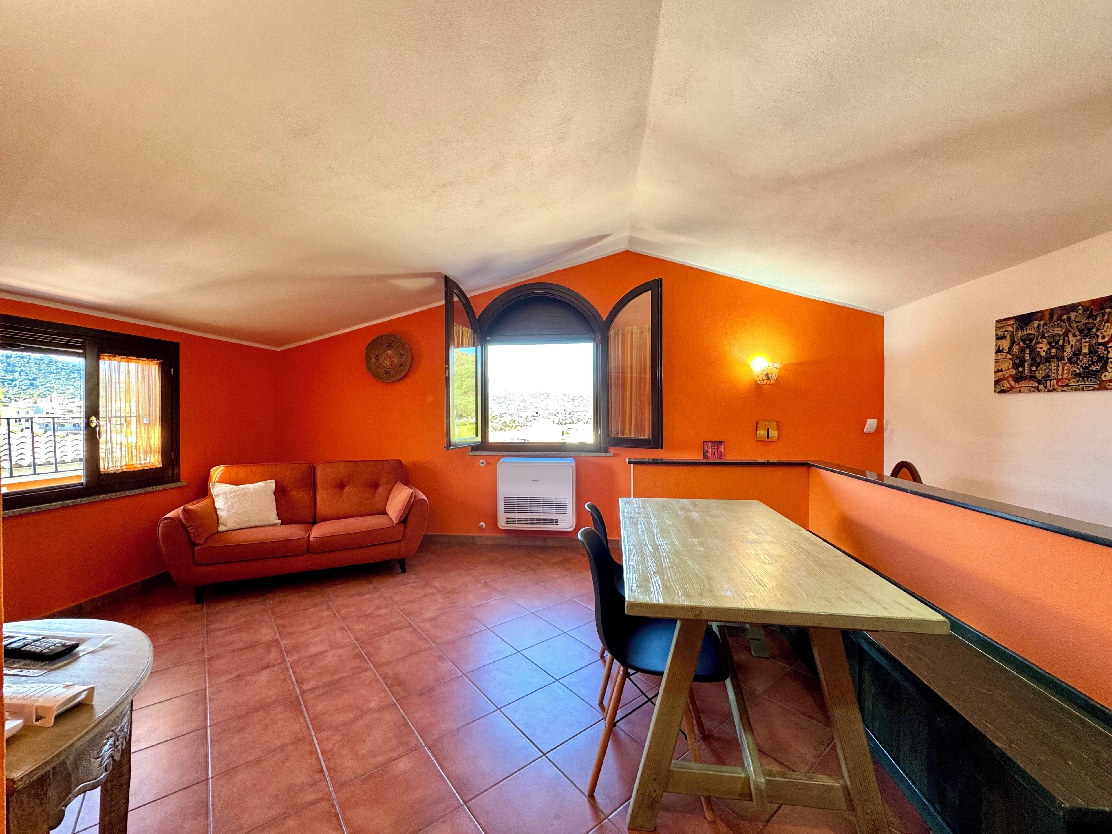Un espace de vie compact comprenant un canapé, une table à manger et une fenêtre avec des rideaux.