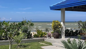 A coastal view with a covered patio area featuring potted plants and a bicycle.