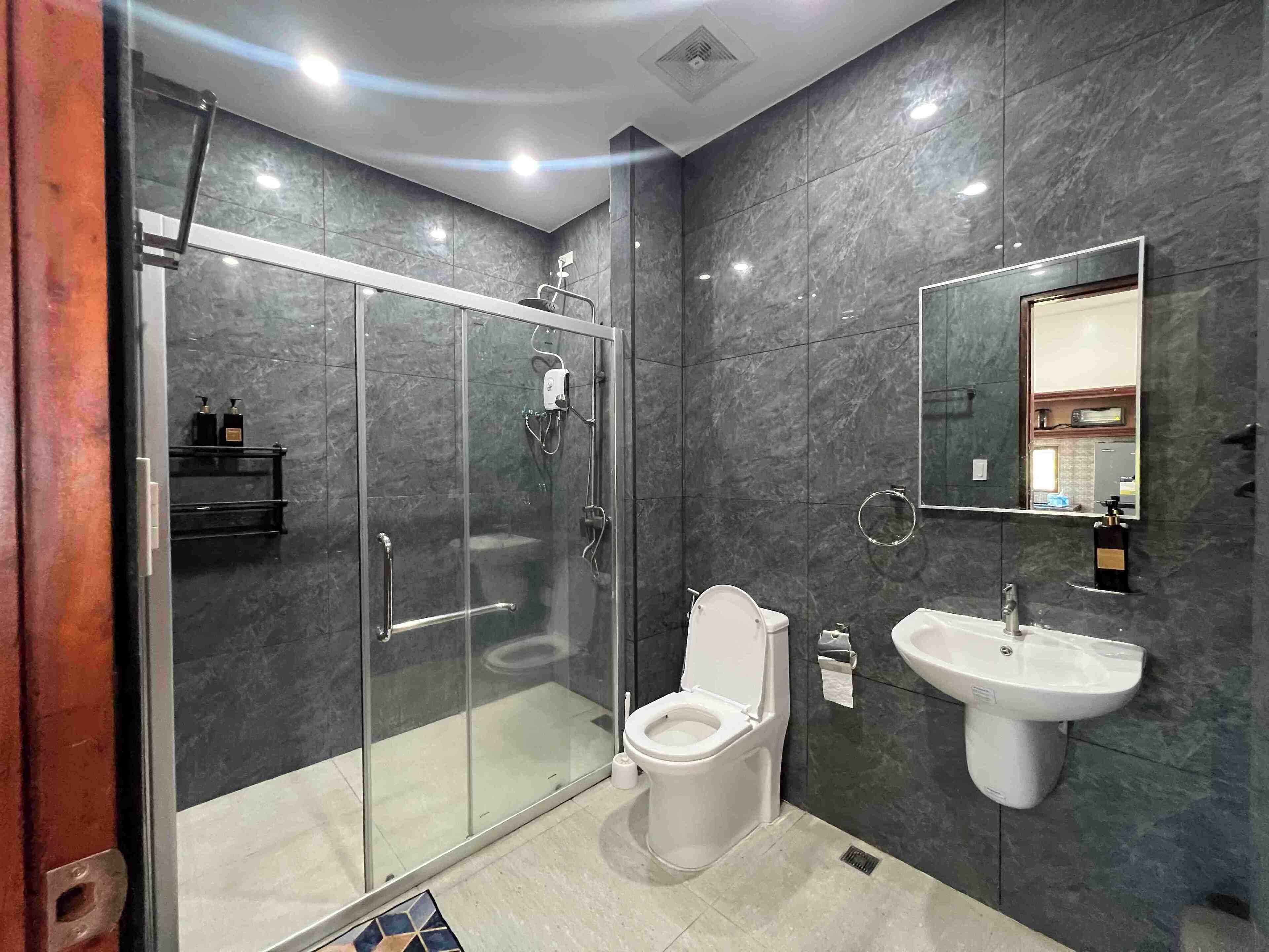 A modern bathroom with a glass-enclosed shower, a toilet, and a sink.