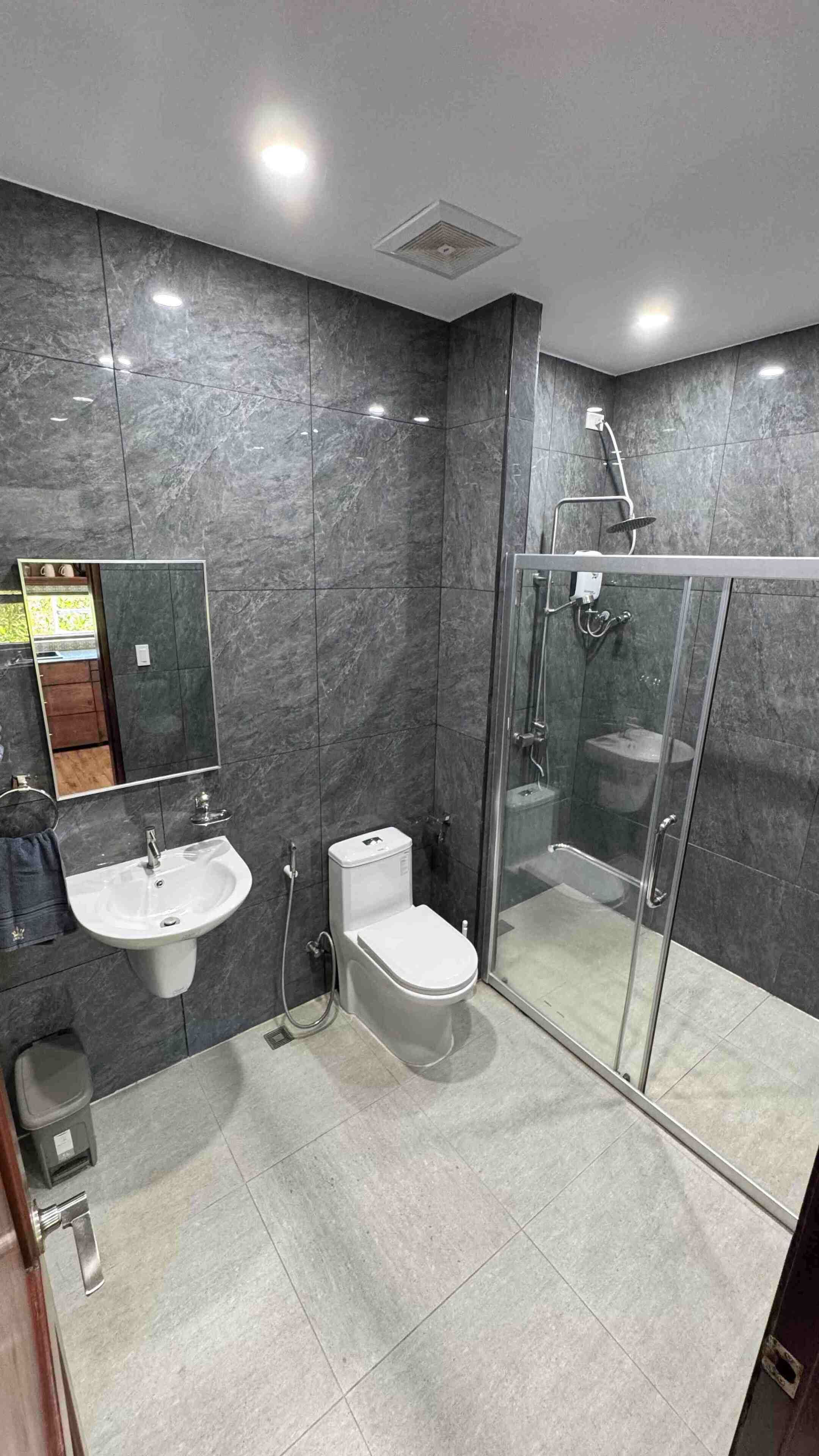 Ein modernes Badezimmer mit einer gläsernen Duschkabine, einem Standwaschbecken und einer Toilette.