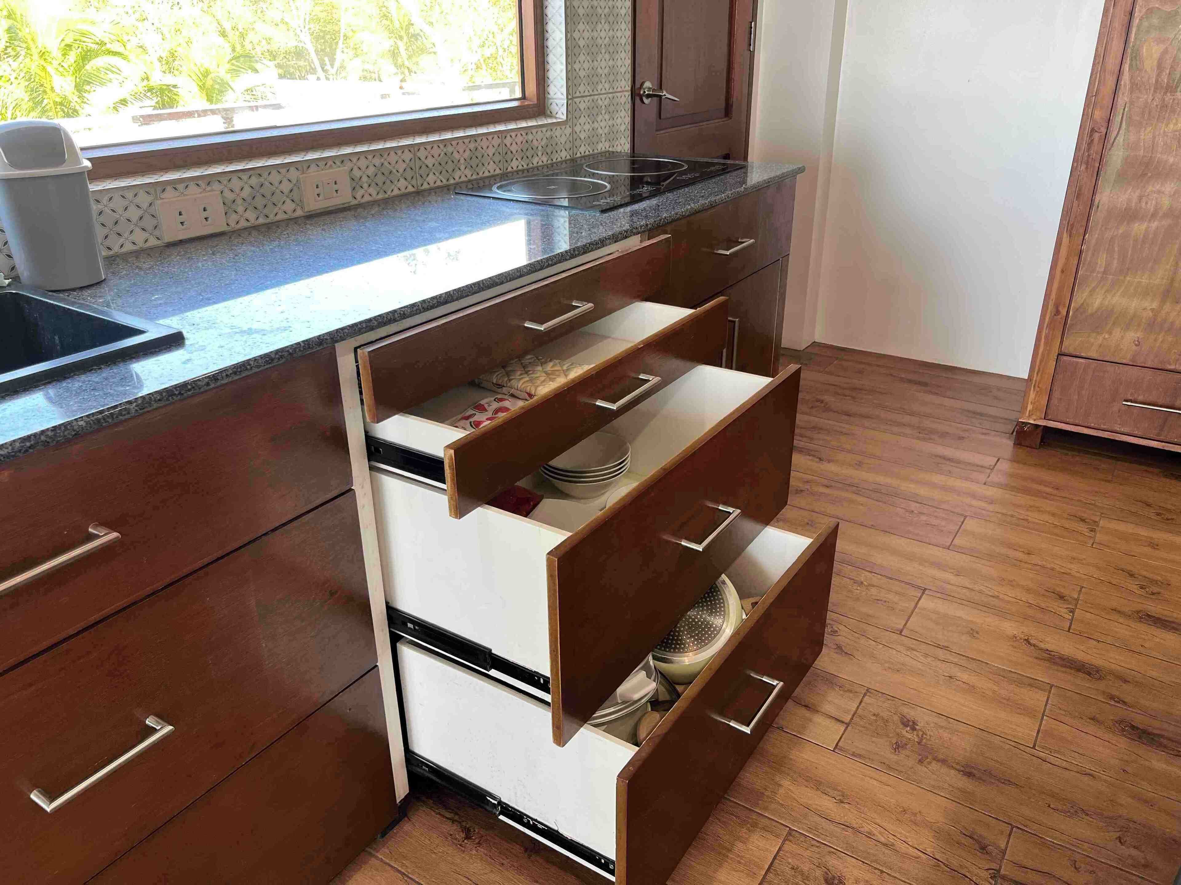 Una cocina con armarios de madera, una encimera y una ventana con vistas a zonas verdes.