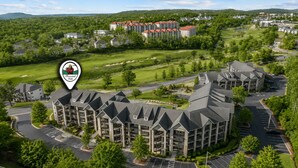A multi-story hotel with a central courtyard, parking, and surrounding greenery. - 3BR Condo at Royal Links • Golf Course Views • Near Hwy 76 (Branson)