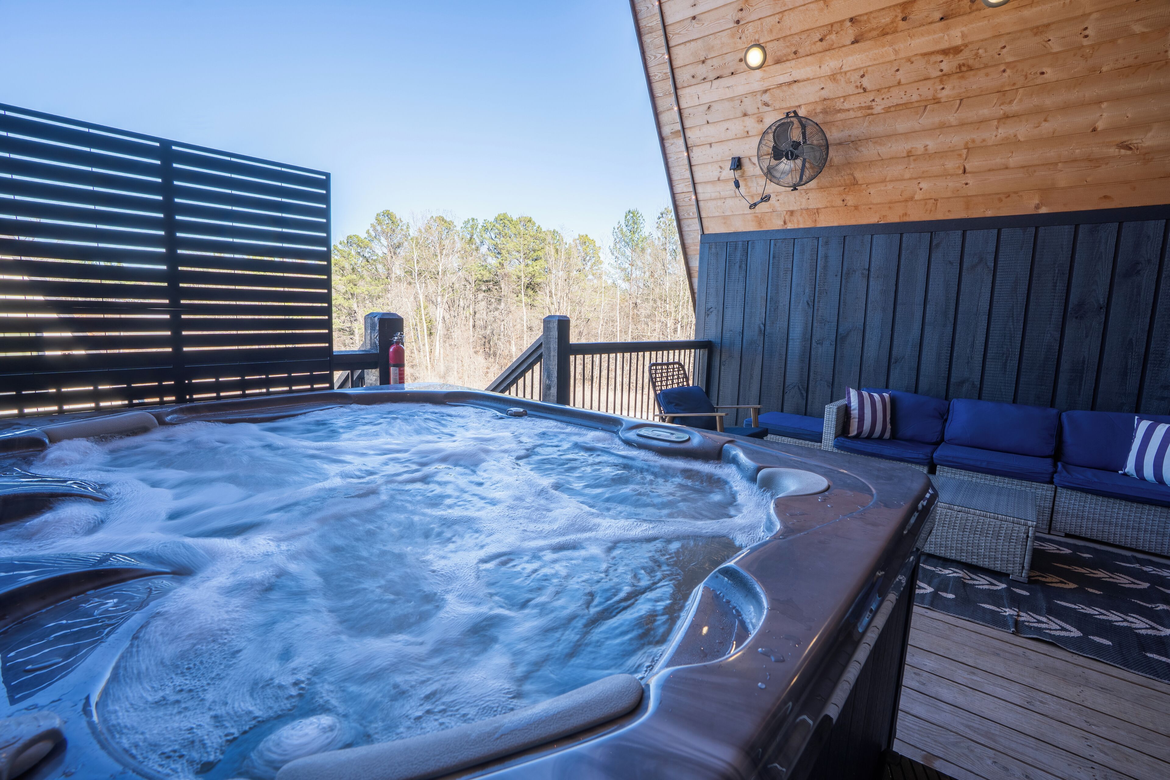 Een hottub op een houten terras, met uitzicht op bomen.