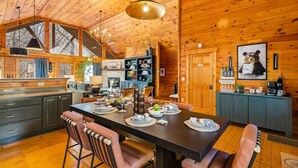 Ein Holzblockhaus-Interieur mit Essbereich, Küche und einem gemütlichen Kamin.