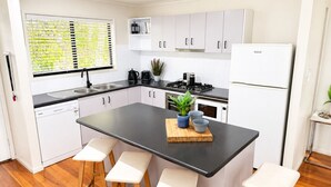 Una cucina moderna con mobili bianchi, un piano di lavoro nero e sgabelli in legno.