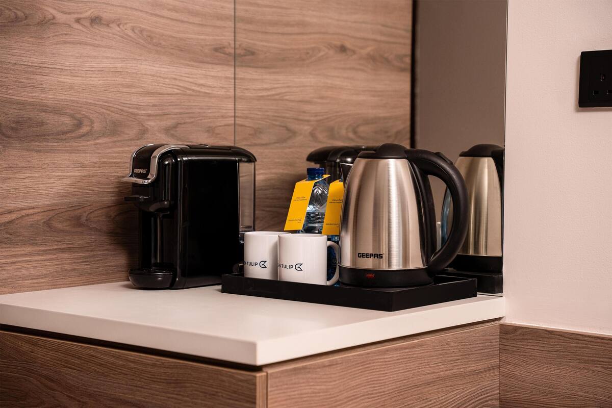 Angolo caffè con una macchina da caffè, un bollitore e due tazze da caffè su un bancone.