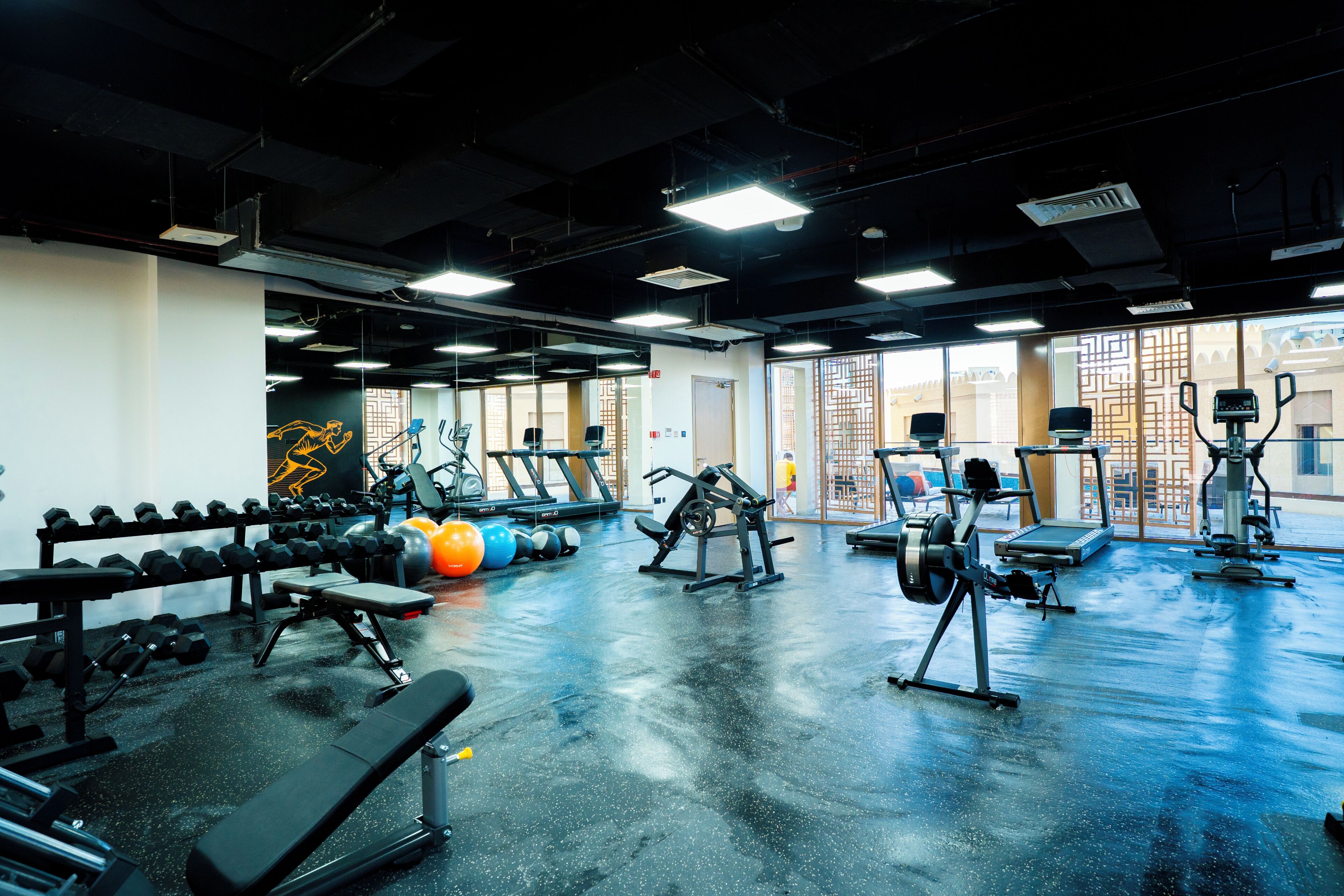 Un gimnasio con equipo de ejercicio, bancos y un espejo grande.
