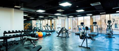 Un gimnasio con equipo de ejercicio, bancos y un espejo grande.