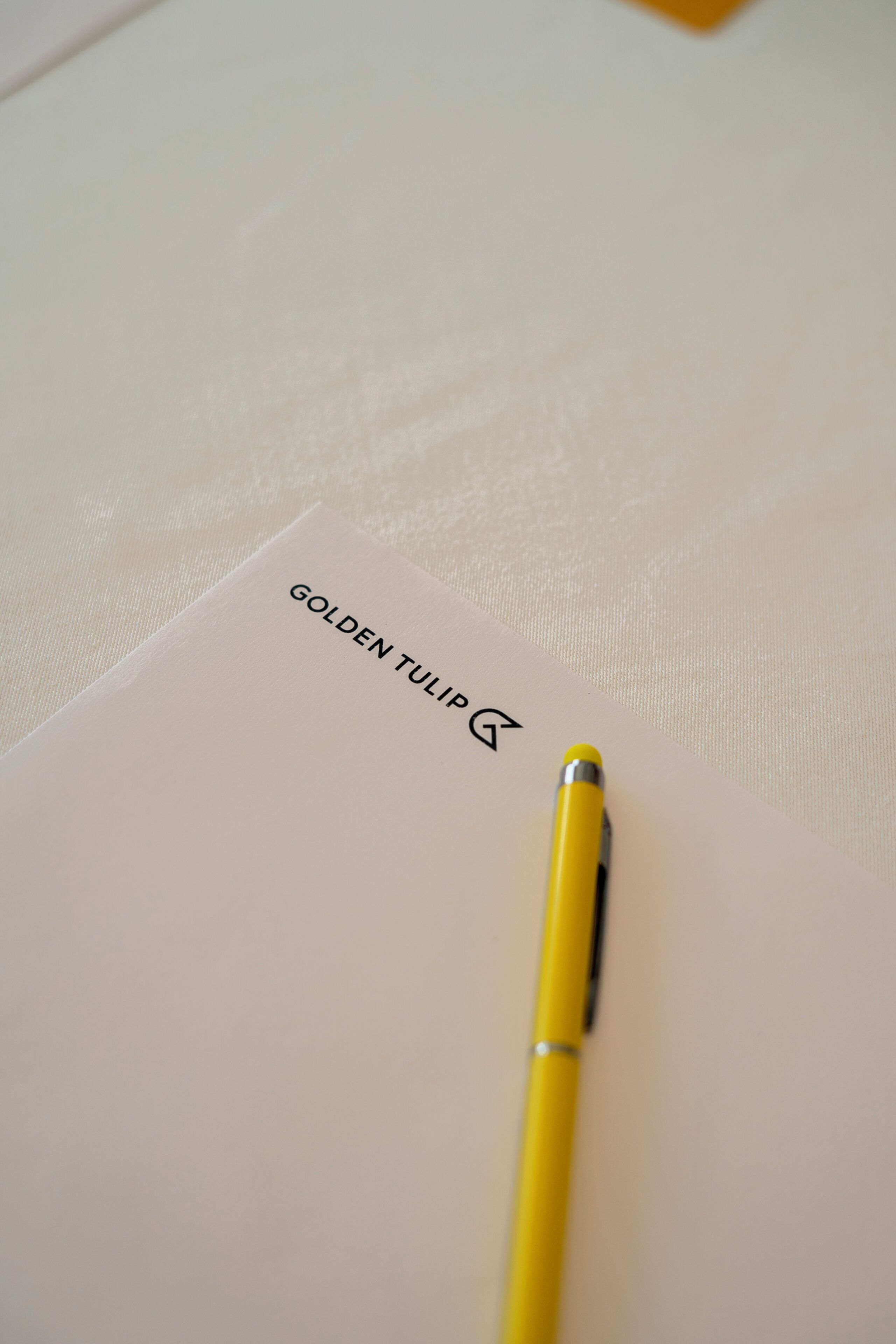 Un stylo jaune sur une feuille de papier, avec le texte « TULIPE DORÉE » et un symbole.