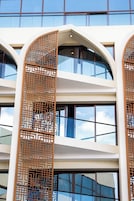 A modern building with multiple floors, large windows, and decorative wooden lattice panels.