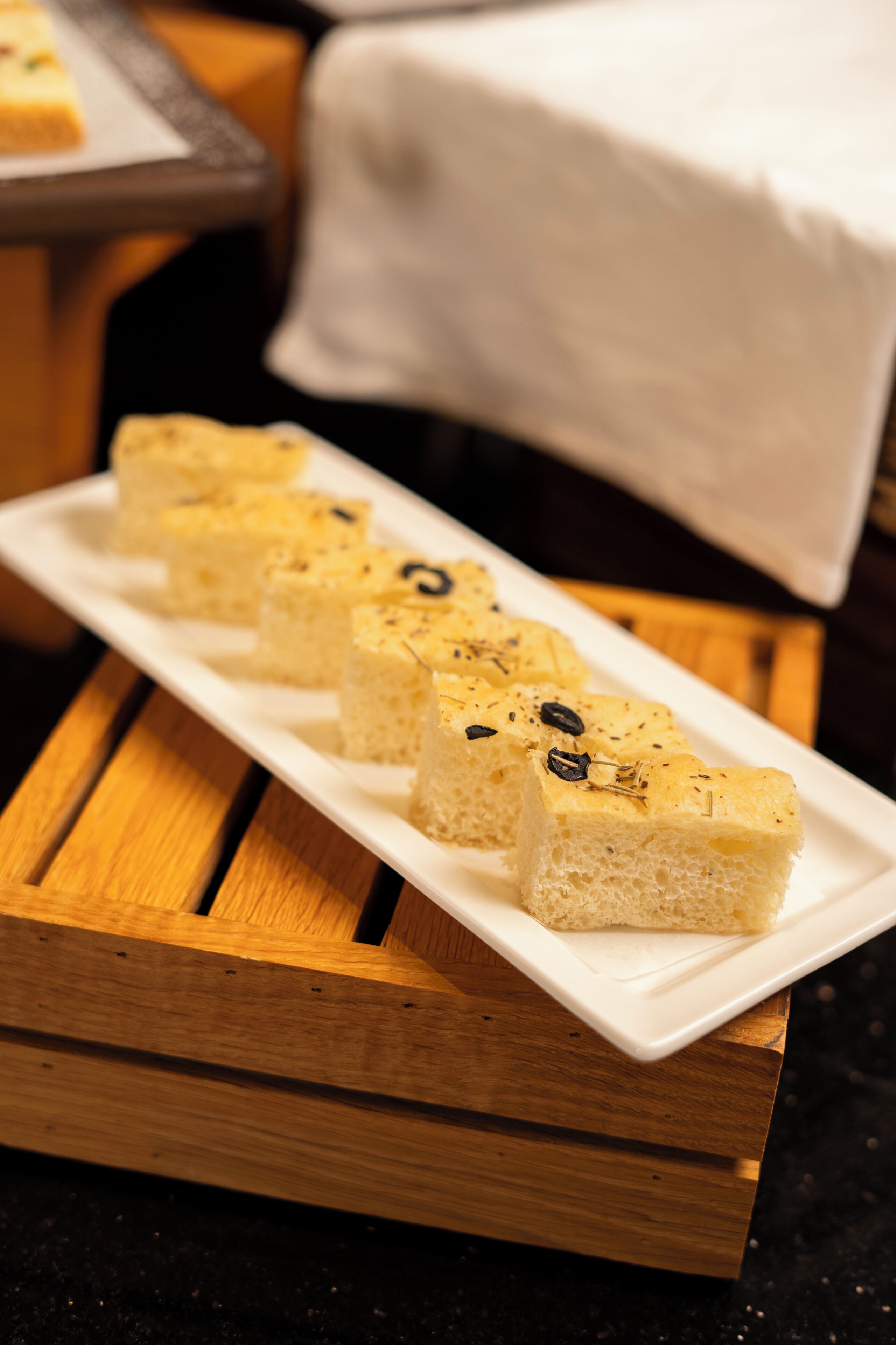 A white rectangular plate with several square pieces of food on a wooden surface.