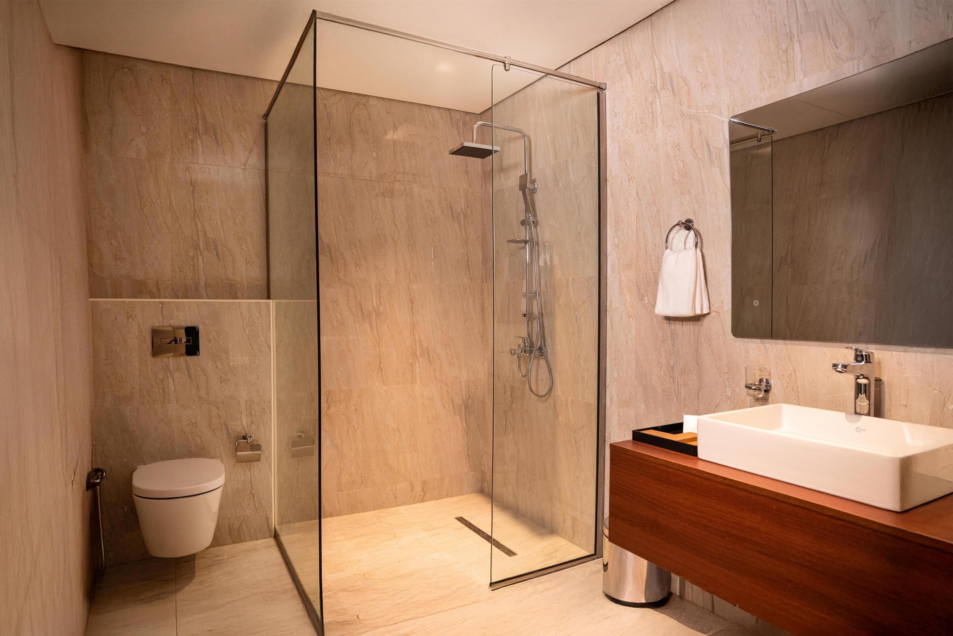 A modern bathroom with a glass-enclosed shower, a wooden vanity, and a large mirror.