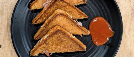 Cuatro sándwiches a la plancha sobre un plato negro, acompañados de salsa.