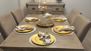 Een eettafel gedekt met gouden en witte borden, servetten en een bloevas.