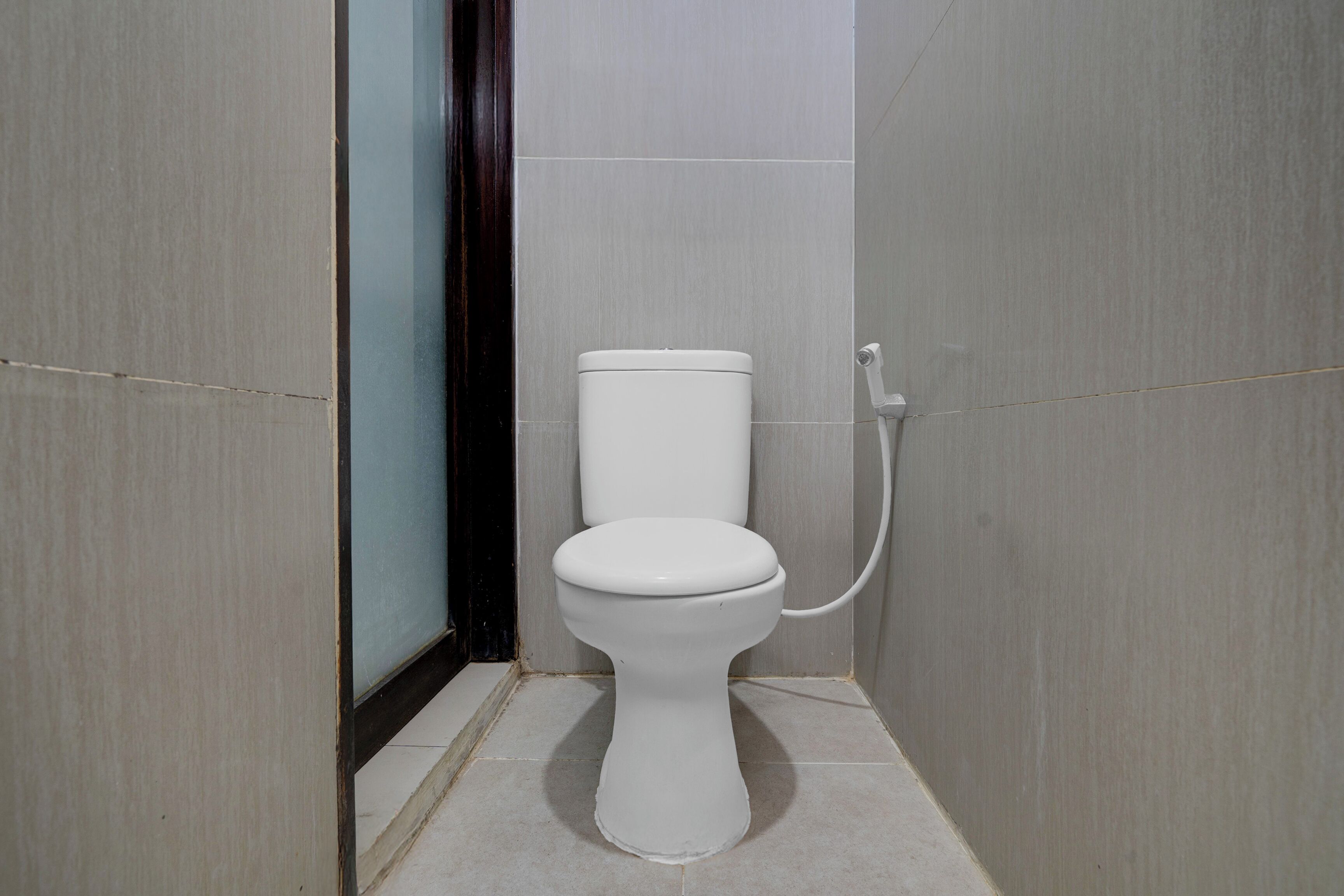 Een compacte, moderne badkamer met een wit toilet, een douchegedeelte en betegelde wanden.