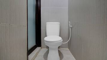 Een compacte, moderne badkamer met een wit toilet, een douchegedeelte en betegelde wanden.