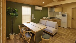 A compact living space with a dining area, a sofa, a small kitchen, and a potted plant. - Solana Smart INN Fuji Kawaguchiko (Fujiyoshida)