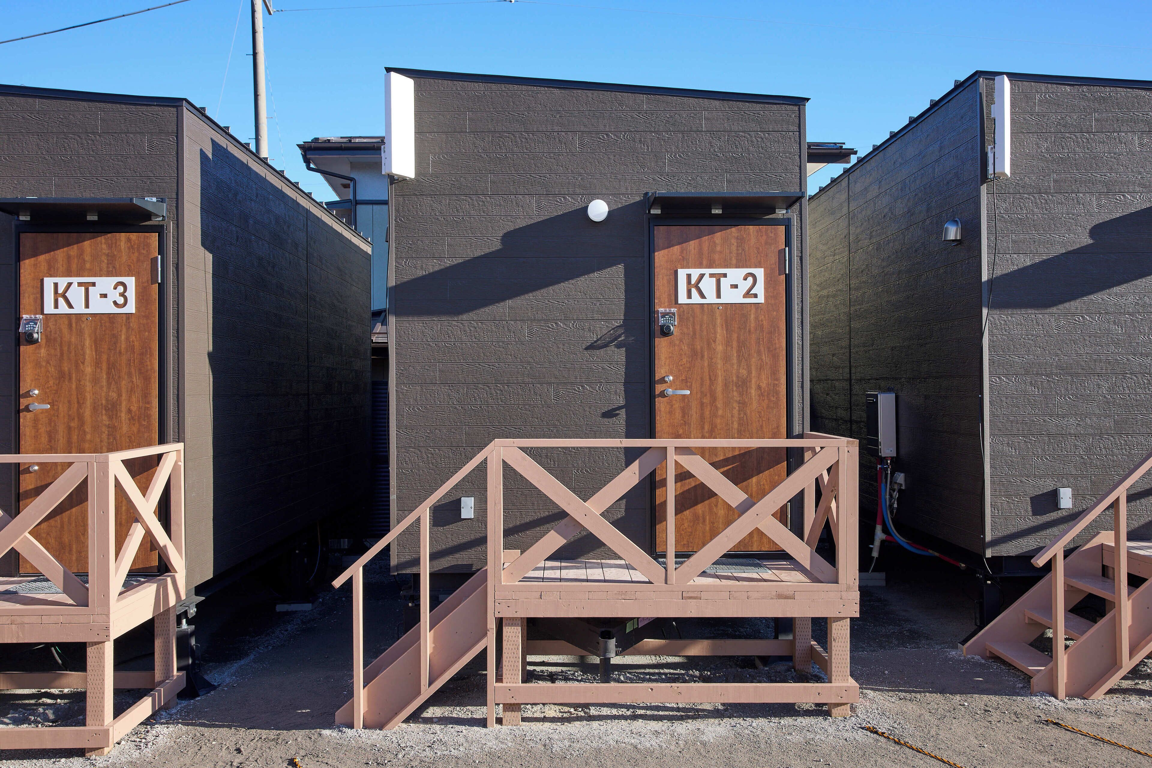 Portable portable toilets labeled KT-2 and KT-3 with wooden railings.