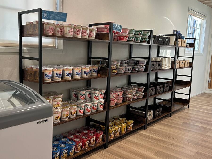 A storage area with shelves filled with canned goods and a refrigerated display case.