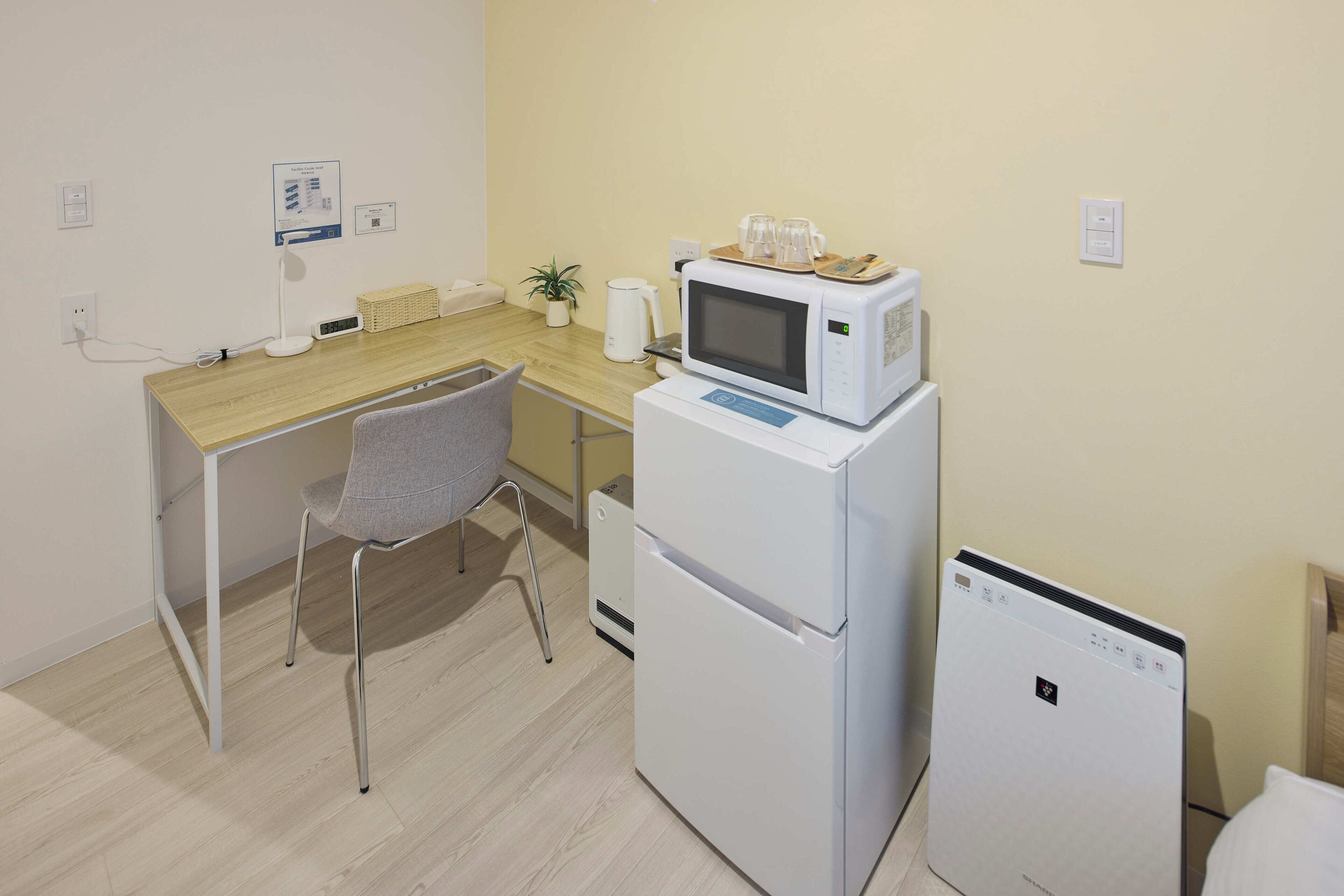A compact kitchenette with a microwave, refrigerator, and a small table with a chair.