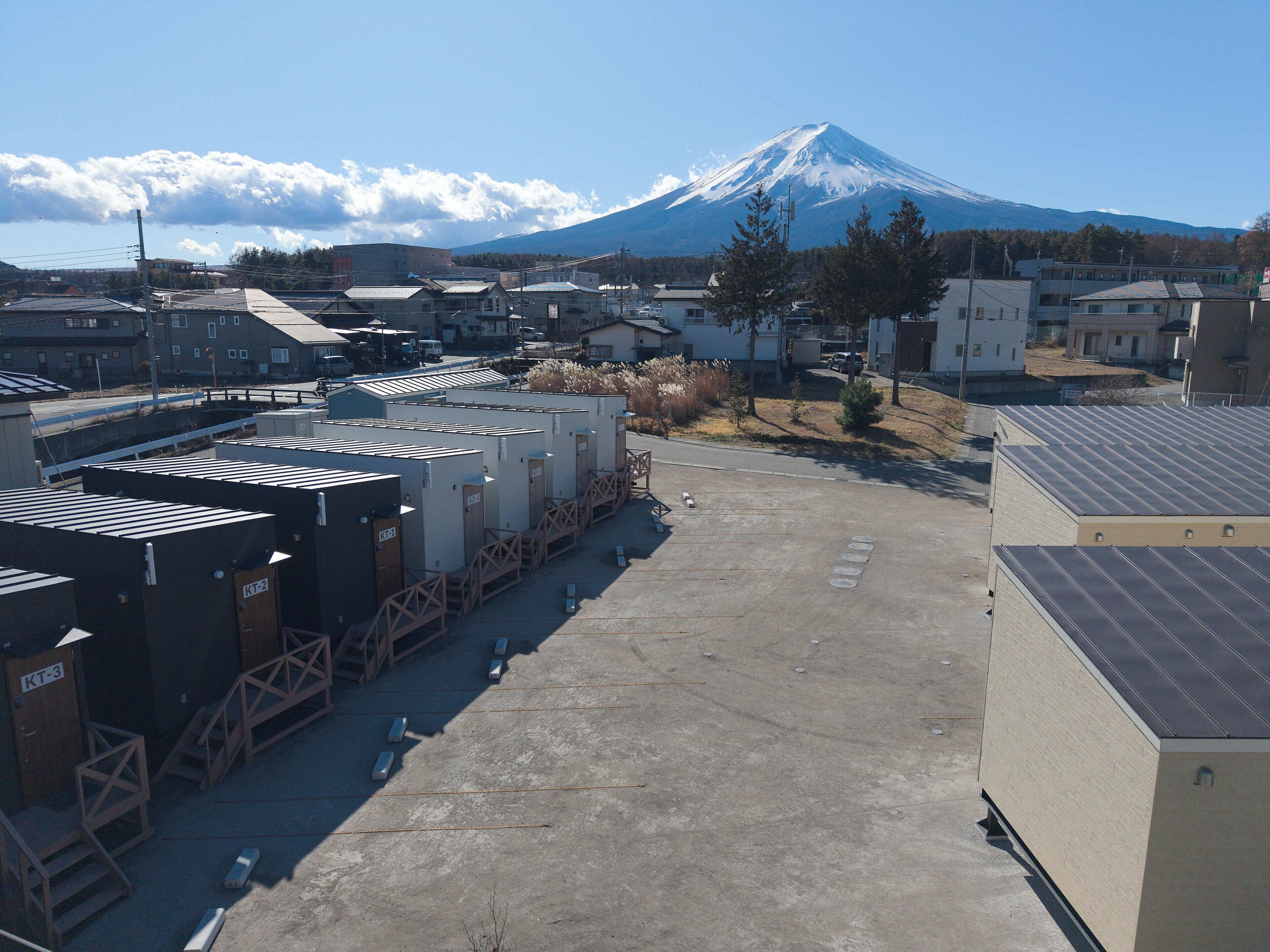 Un estacionamiento con edificios modulares, vista de una montaña y cielo despejado.