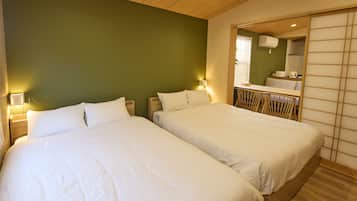 A hotel room with two beds, a wooden ceiling, a green wall, and a mirror reflecting a bathroom.