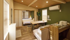 A compact room with a bed, a dining table, a sofa, a small trash bin, and a kitchenette area with a coffee maker. - Solana Smart INN Fuji Kawaguchiko (Fujiyoshida)