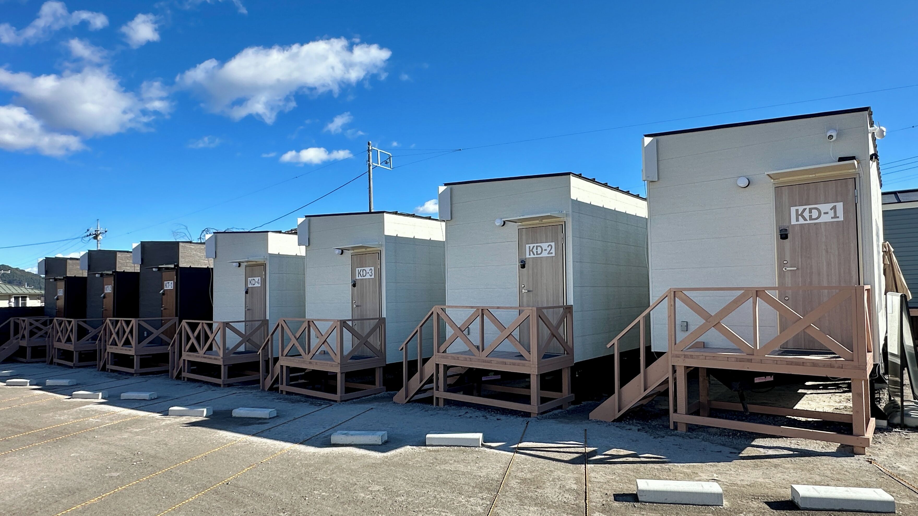 Portable cabins labeled KD-1 to KD-4, each with a wooden staircase and a door.