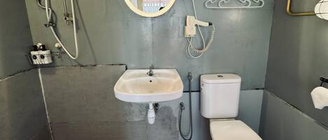 Un baño pequeño con lavamanos, inodoro y ducha blancos.