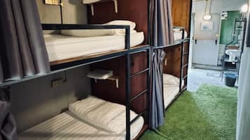 A compact room with bunk beds, a small kitchenette, and a bathroom.