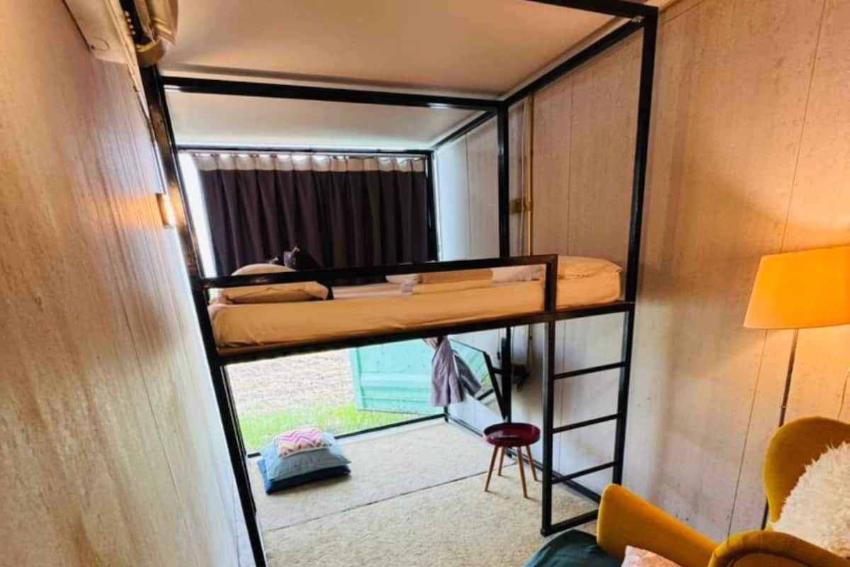 A compact room with bunk beds, a yellow armchair, a small table, and a lamp.