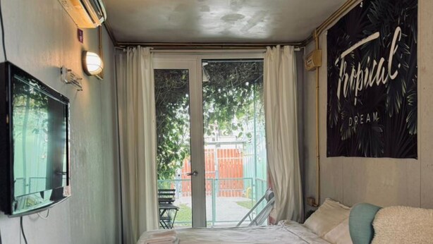 A bedroom with a bed, a chair, a TV, and a window with curtains. - Padi Box (Sekinchan)