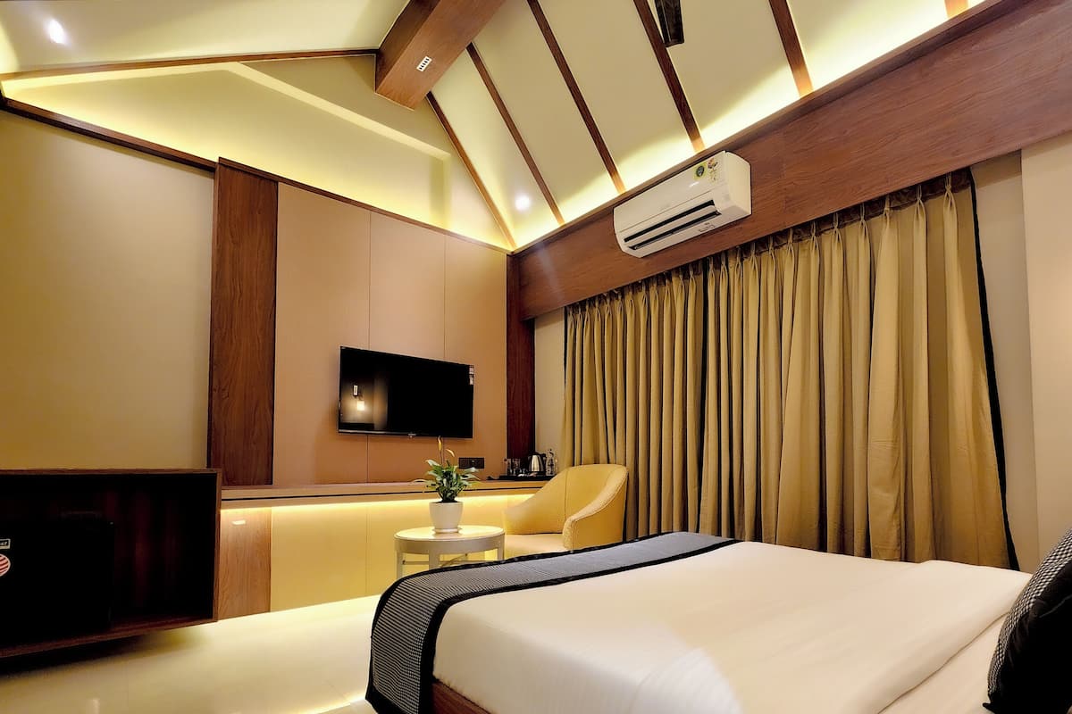 A modern hotel room with a large bed, a flat-screen TV, a small table with a plant, and a sofa.