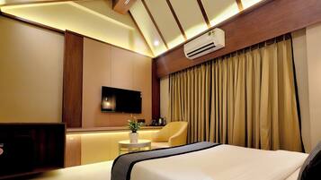 A modern hotel room with a large bed, a flat-screen TV, a small table with a plant, and a sofa.
