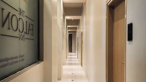 Un couloir d’hôtel avec une pancarte sur le côté gauche, une porte en bois sur le côté droit et un sol carrelé.