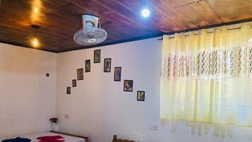 A room with two wooden beds, a ceiling fan, and a wall with framed pictures.