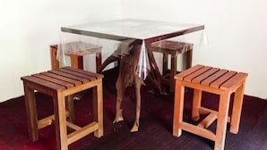 Un comedor con una mesa de vidrio rodeada de sillas de madera y un taburete de madera.