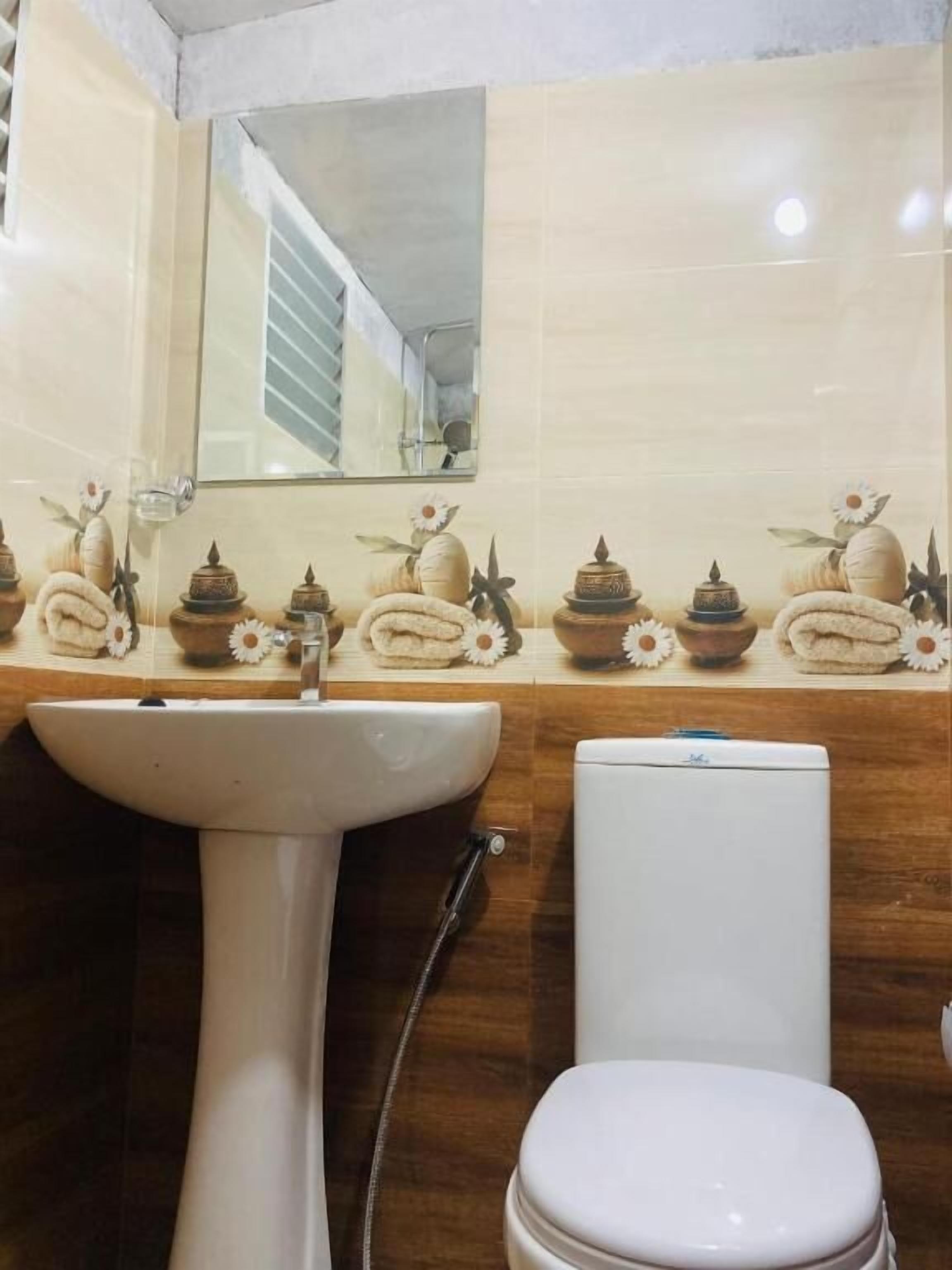 Un baño con lavamanos pedestal, inodoro y espejo sobre el lavamanos.