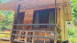 Una construcción de madera con balcón, rodeada de abundante vegetación.